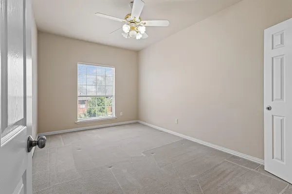 an empty room with windows and fan