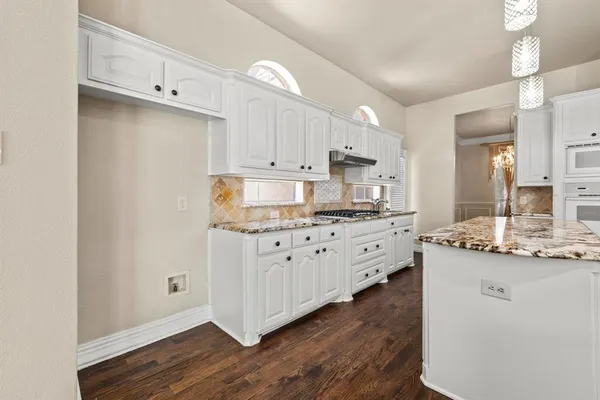a kitchen with granite countertop a sink cabinets and wooden floor