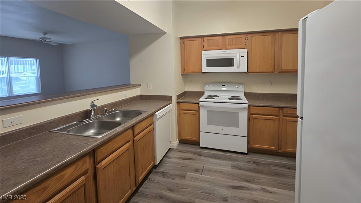 6650 West Warm Springs Road, Unit 1064 Las Vegas, NV 89118 - Photo 2 of 10 Kitchen with white appliances, dark countertops, dark wood finished floors, ceiling fan, and brown cabinetry