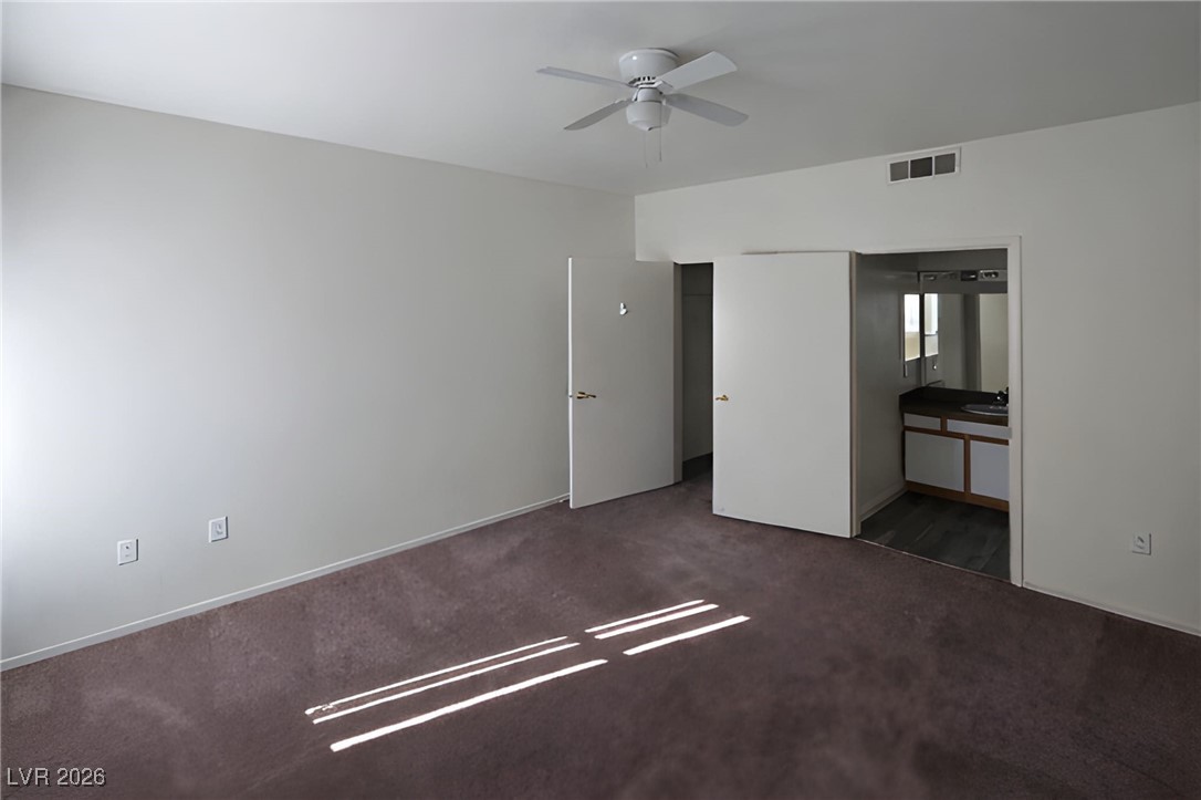 6650 West Warm Springs Road, Unit 1064 Las Vegas, NV 89118 - Photo 5 of 10 Unfurnished bedroom featuring carpet, a ceiling fan, and connected bathroom