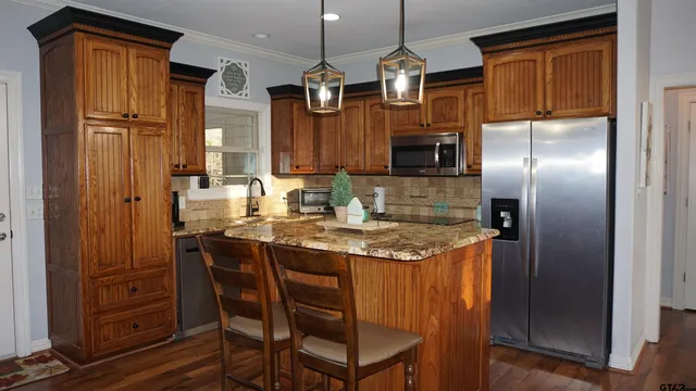a kitchen with stainless steel appliances granite countertop a refrigerator a stove and a sink with wooden floor