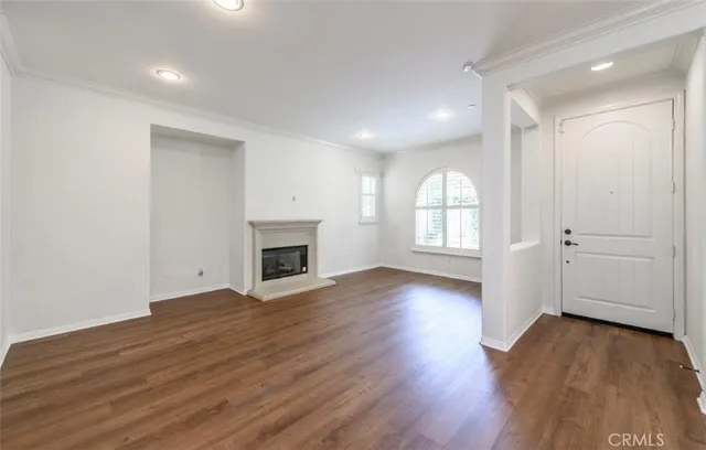 an empty room with wooden floor fireplace and windows