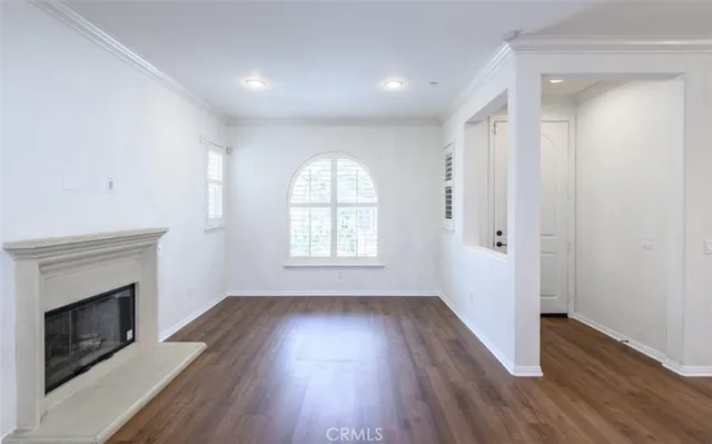 an empty room with wooden floor cabinet and windows