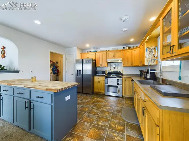 a kitchen with stainless steel appliances granite countertop a stove a sink a refrigerator and island
