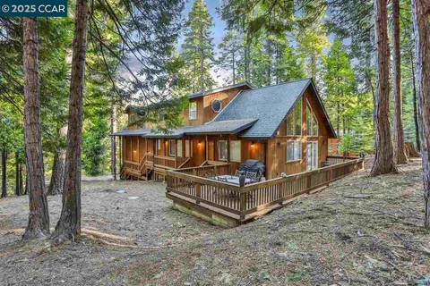 a view of a house with a yard deck and a large tree