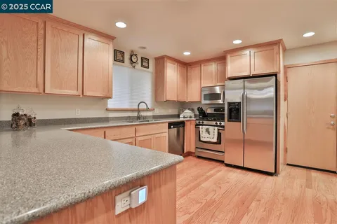 a kitchen with stainless steel appliances granite countertop a refrigerator a sink a stove and oven