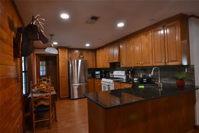 a kitchen with stainless steel appliances granite countertop a refrigerator a stove and a sink with granite countertops