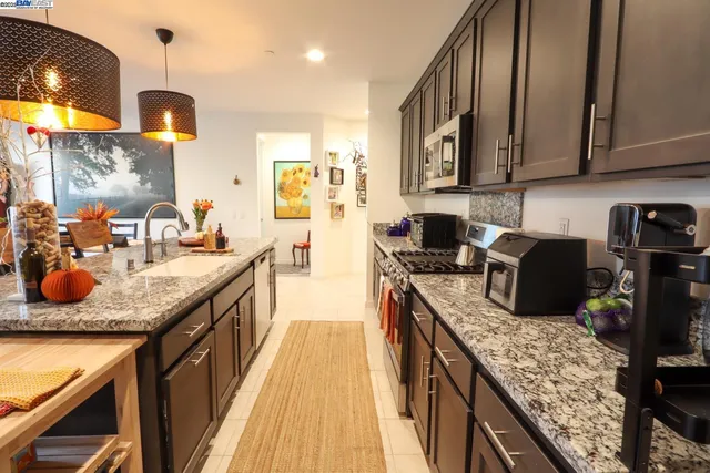 a kitchen with stainless steel appliances granite countertop a sink a stove and a wooden cabinets