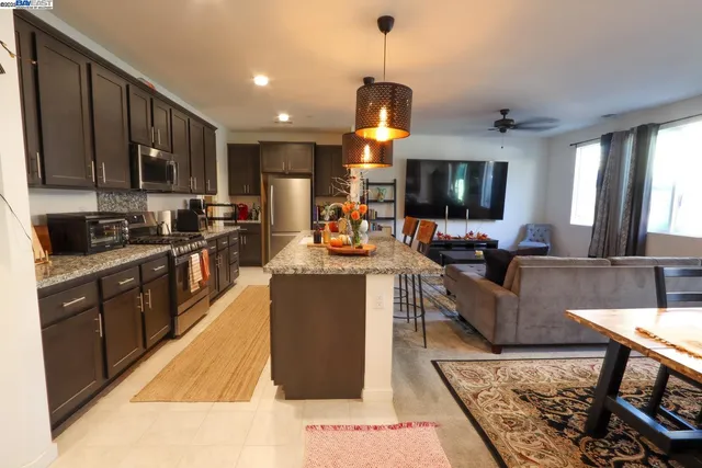 a kitchen with stainless steel appliances kitchen island granite countertop a sink a stove a dining table and chairs