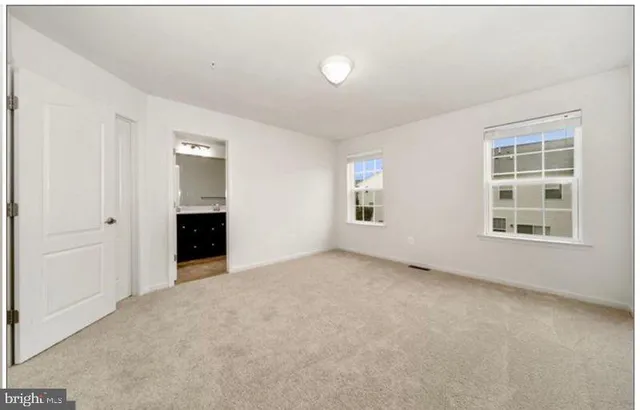 an empty room with windows and fireplace