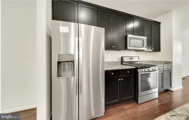 a kitchen with stainless steel appliances granite countertop a refrigerator and a stove top oven