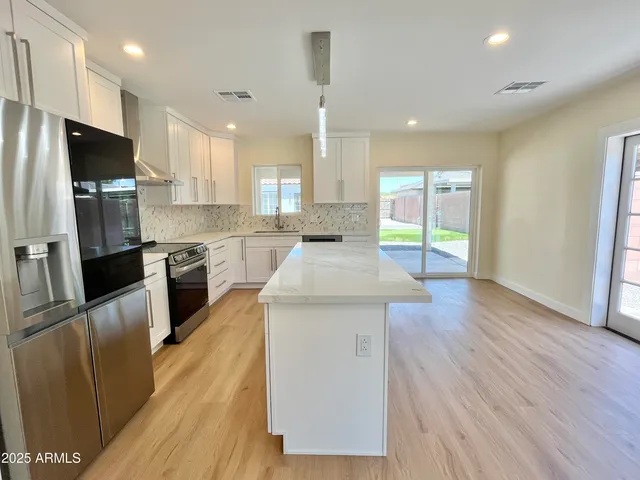 a view of kitchen with stainless steel appliances wooden floor and living room