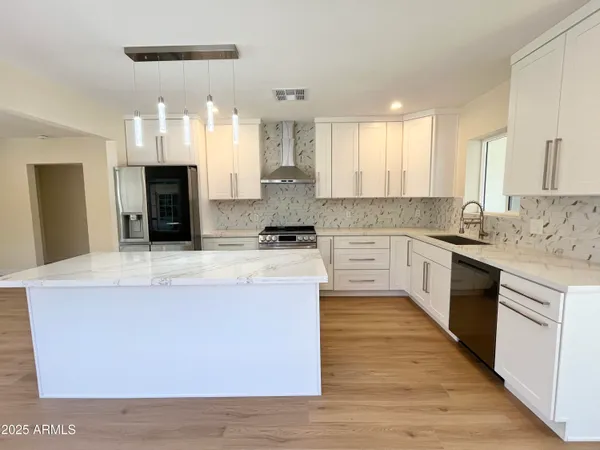 a kitchen with granite countertop a refrigerator sink and cabinets