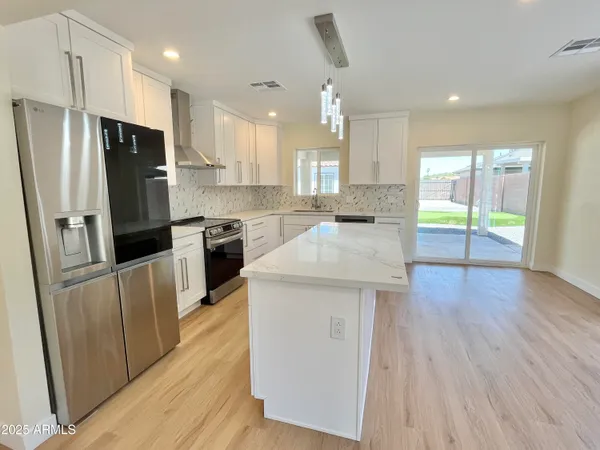 a kitchen with stainless steel appliances granite countertop a stove top oven a sink dishwasher a refrigerator and a microwave oven with wooden floor