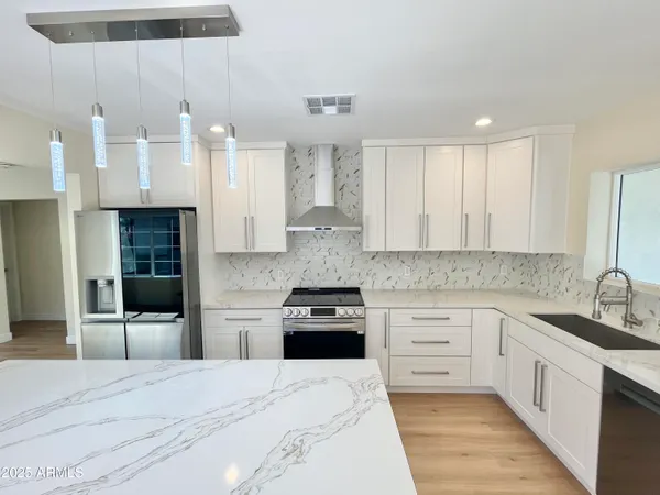 a large kitchen with stainless steel appliances granite countertop a stove a sink and a refrigerator