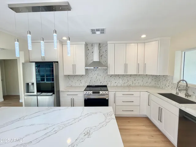 a large kitchen with stainless steel appliances granite countertop a stove a sink and a refrigerator