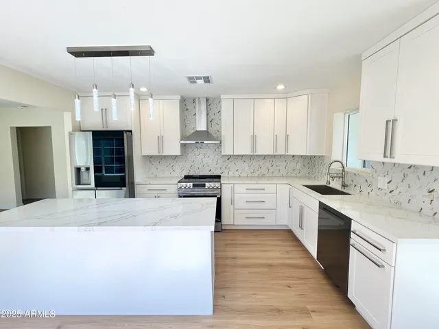 a kitchen with granite countertop a stove a sink a refrigerator and wooden floor