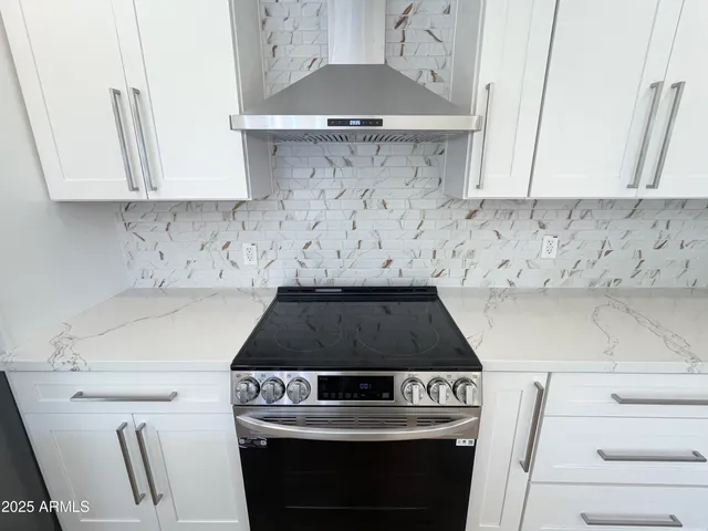 a large kitchen with stainless steel appliances kitchen island granite countertop a stove top oven a sink and white cabinets