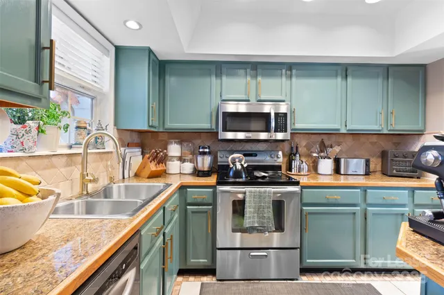 a kitchen with stainless steel appliances granite countertop a sink a stove and a microwave