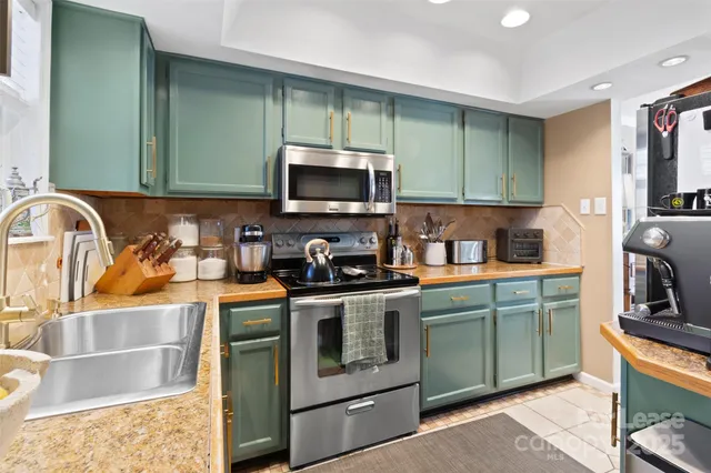 a kitchen with stainless steel appliances granite countertop a sink and a stove top oven