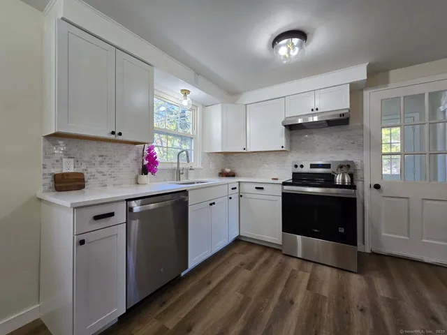 a kitchen with granite countertop a sink cabinets and stainless steel appliances