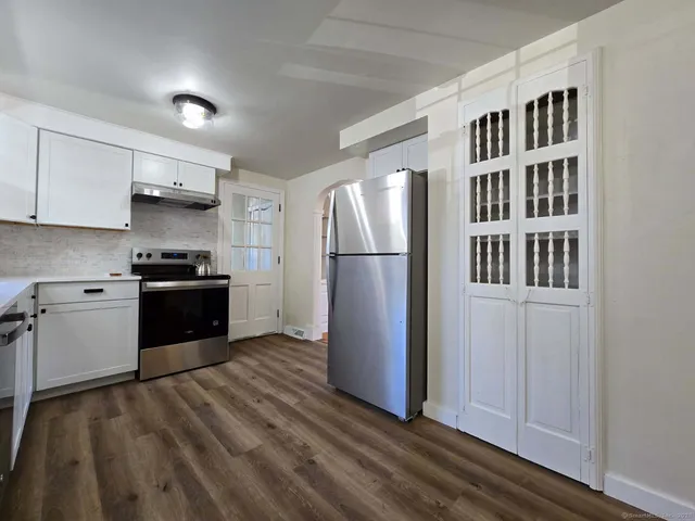 a kitchen with granite countertop a refrigerator and a stove top oven