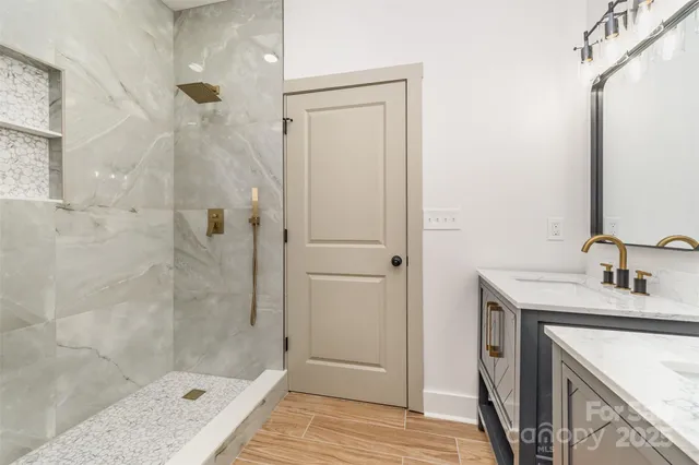 a bathroom with a granite countertop sink a mirror and shower