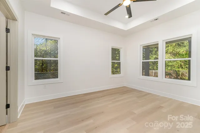 a view of an empty room with a window and wooden floor