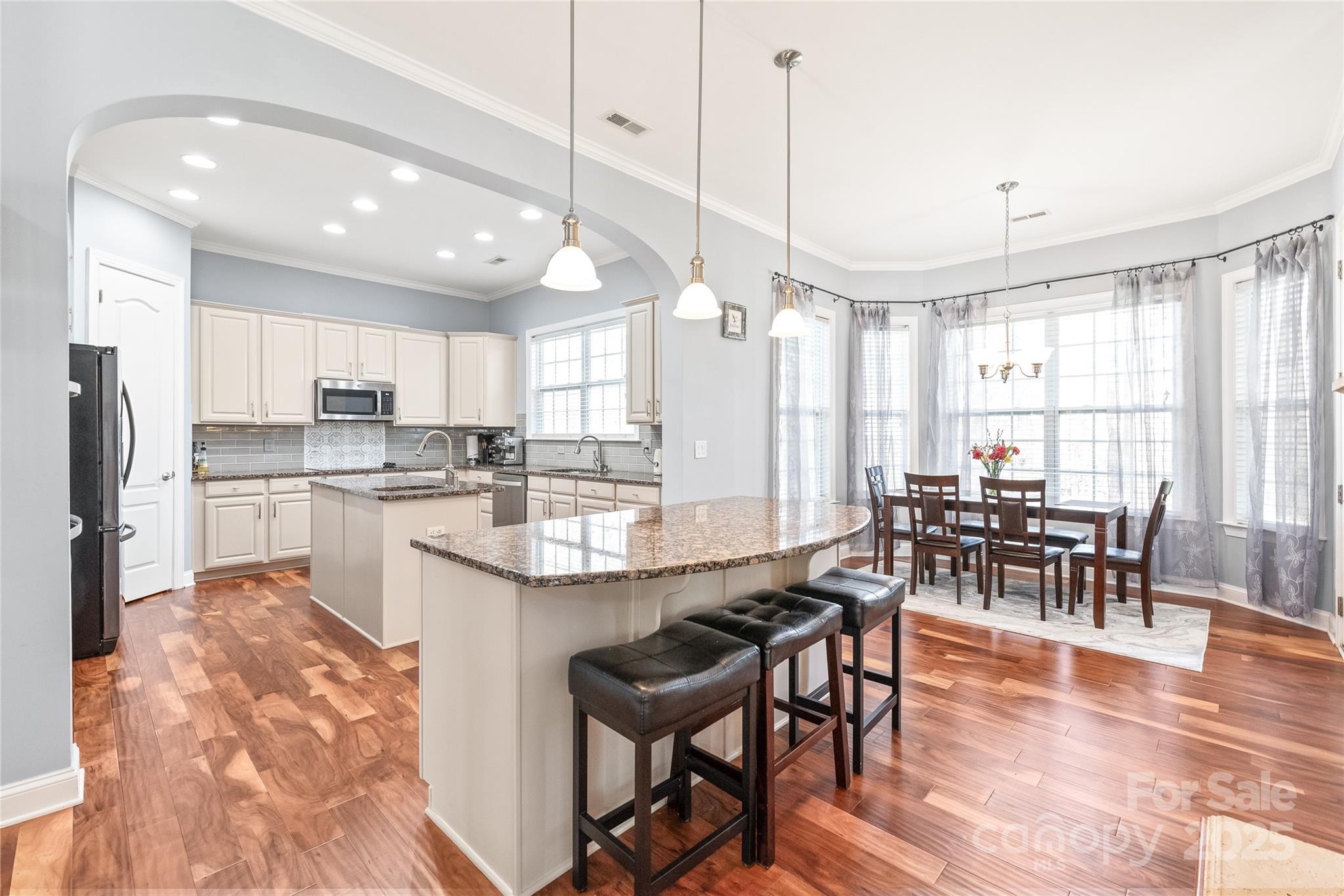8504 Soaring Eagle Lane Waxhaw, NC 28173 - Photo 13 of 48 a open kitchen with stainless steel appliances granite countertop a stove a refrigerator a kitchen island a dining table and chairs with wooden floor