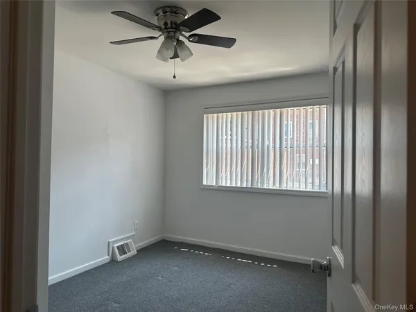 an empty room with a window and a fan