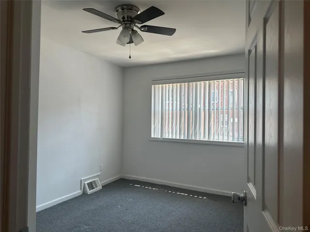 an empty room with a window and a fan