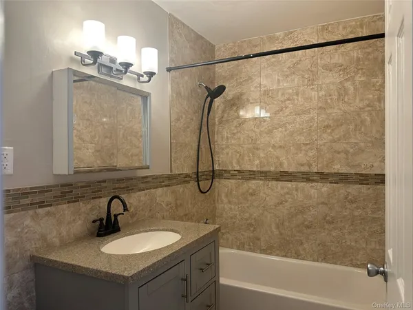 a bathroom with a sink vanity granite tub shower and a mirror