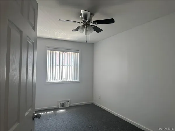 an empty room with a window and a fan