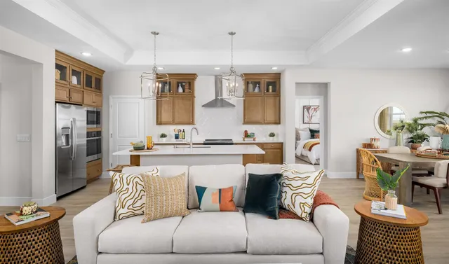 a living room with furniture a chandelier and kitchen view
