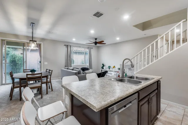 a kitchen with stainless steel appliances granite countertop a refrigerator a sink a stove a dining table and chairs