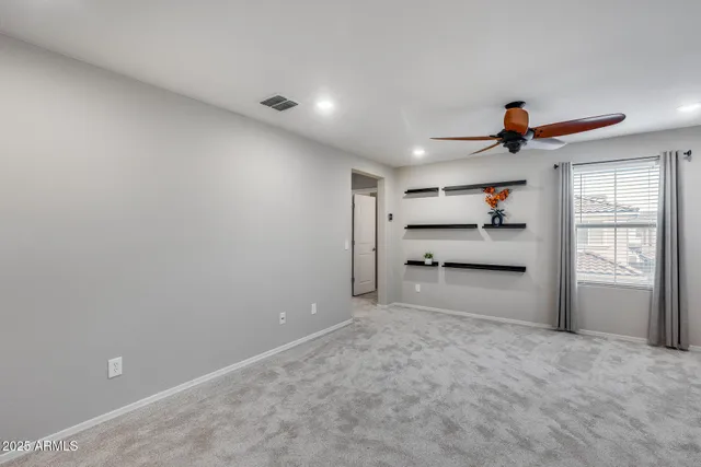 an empty room with windows and ceiling fan
