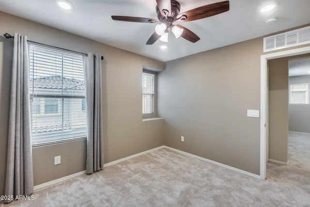 an empty room with windows and fan