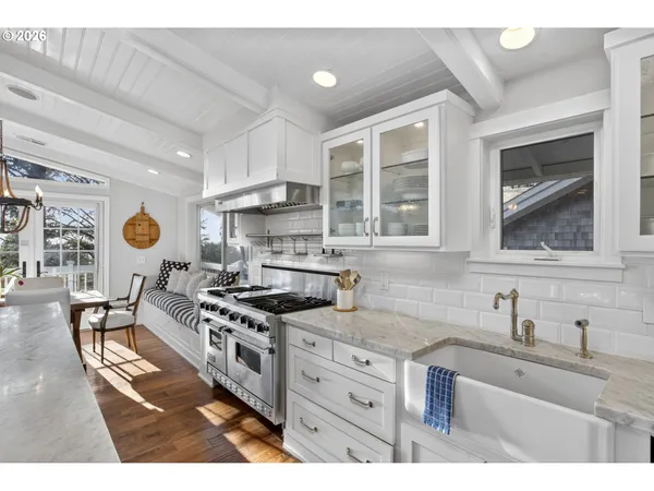 a kitchen with stainless steel appliances granite countertop a stove a sink dishwasher and white cabinets with wooden floor
