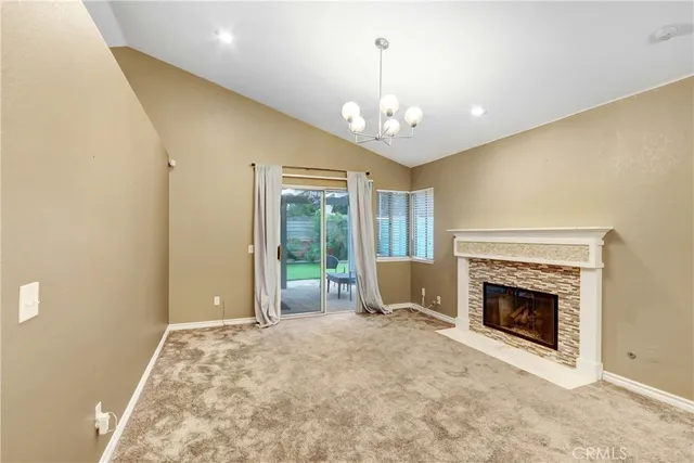 a view of a livingroom with a fireplace a chandelier and windows