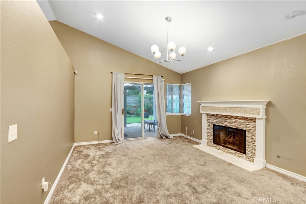 7622 Belpine Place Rancho Cucamonga, CA 91730 - Photo 4 of 15 a view of a livingroom with a fireplace a chandelier and windows