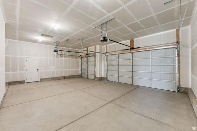 1004 West Paramount Cove South, Unit 315 Ogden, UT 84405 - Photo 34 of 42 Spacious three-car garage featuring automatic overhead doors, a pedestrian door, and overhead lighting