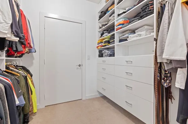 a view of walk in closet with clothes and shoes