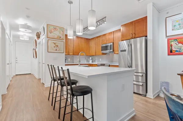 a kitchen with stainless steel appliances kitchen island granite countertop a refrigerator a sink a stove a dining table and chairs with wooden floor