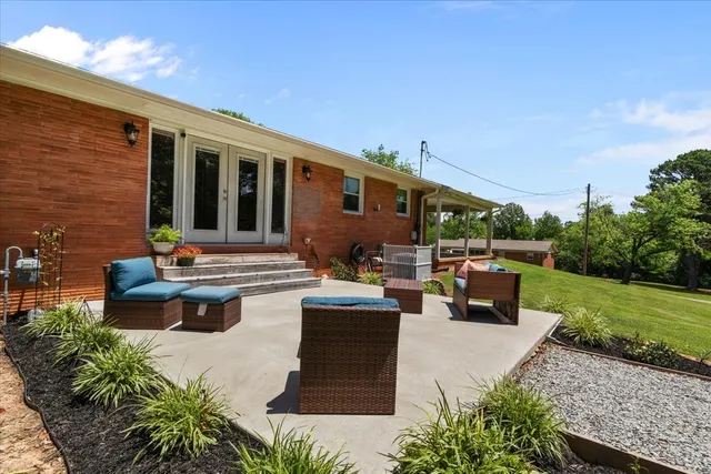 a view of a patio with couches table and chairs with potted plants and big yard