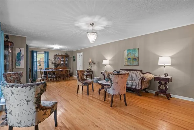 a dining room with wooden floor a chandelier a glass table and chairs