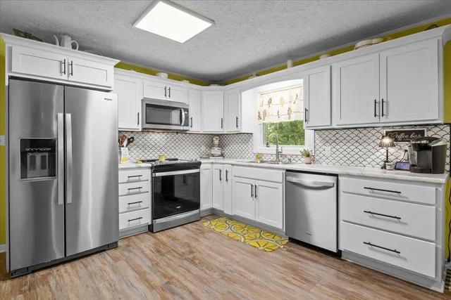 a kitchen with granite countertop a refrigerator stove and microwave