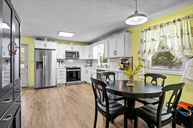 a open kitchen with stainless steel appliances granite countertop a stove refrigerator and a dining table with wooden floor