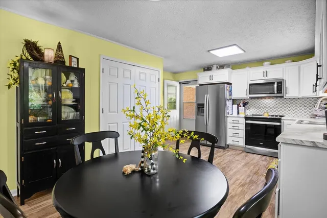 a dining room with furniture a chandelier a kitchen view and appliances