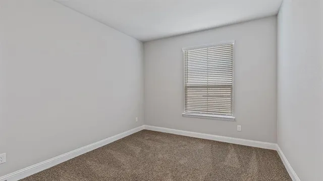 an empty room with chandelier fan and windows