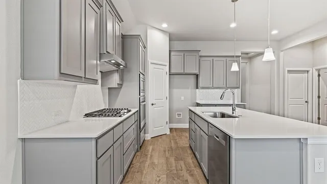 a kitchen with stainless steel appliances a stove a sink cabinets and a chandelier